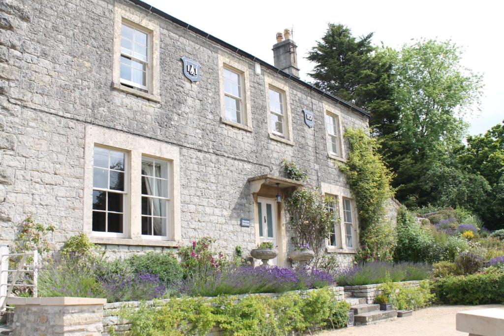 a stone house with flowers in front of it at Roundhill Farmhouse in Bath