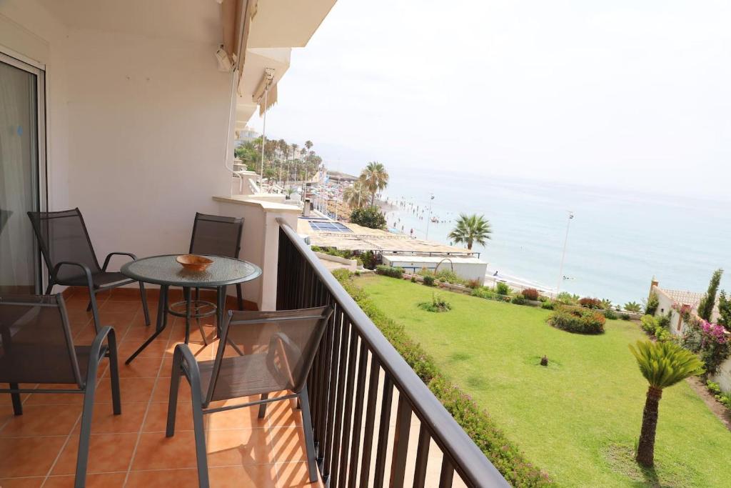 balcón con mesa, sillas y vistas al océano en Apartamento en NERJA. Primera línea de playa en Nerja