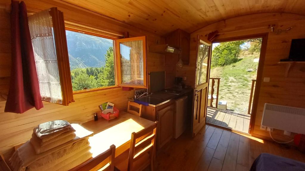 mit Blick auf eine Küche in einer Hütte mit Fenstern in der Unterkunft Les ROULOTTINS in Briançonnet