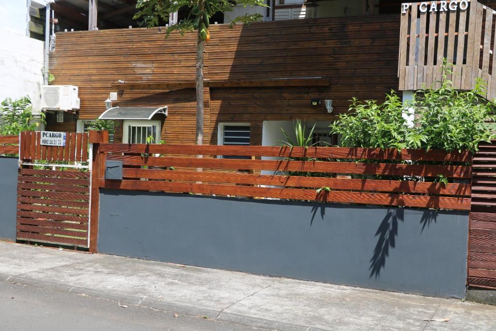 a wooden fence next to a house with plants at Pension Cargo in Bras-Panon