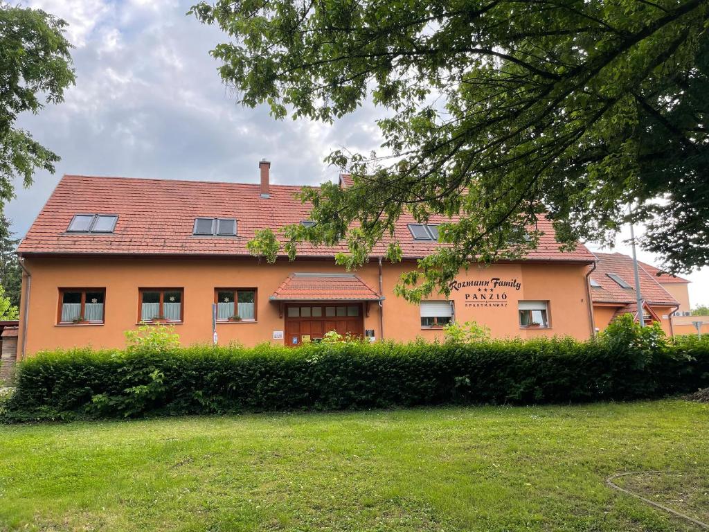 een groot oranje huis met een tuin ervoor bij Rozmann Family Panzió & Apartmanhaz in Sárvár