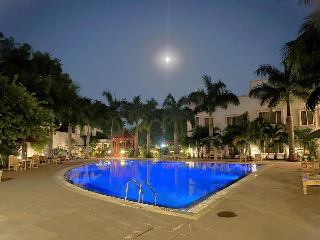 ein Schwimmbad in der Nacht mit dem Mond darüber in der Unterkunft A S Hotels in Khajurāho