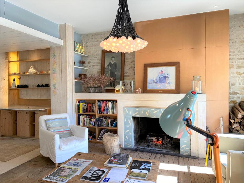 a living room with a fireplace and a chandelier at Hôtel Le Sénéchal in Ars-en-Ré