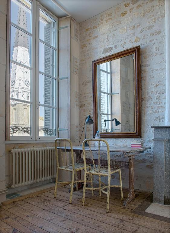 two chairs sitting at a table in a room with a mirror at Hôtel Le Sénéchal in Ars-en-Ré