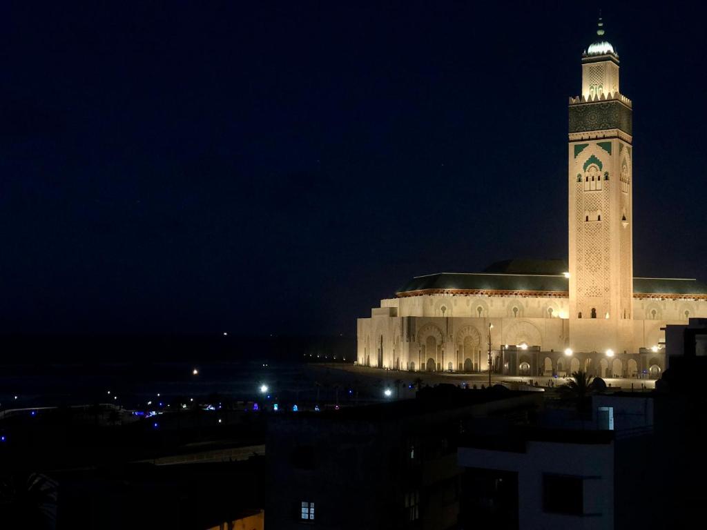 a large building with a clock tower at night at Bel appartement avec une belle vue sur la grande mosquée Hassan II et la mer in Casablanca