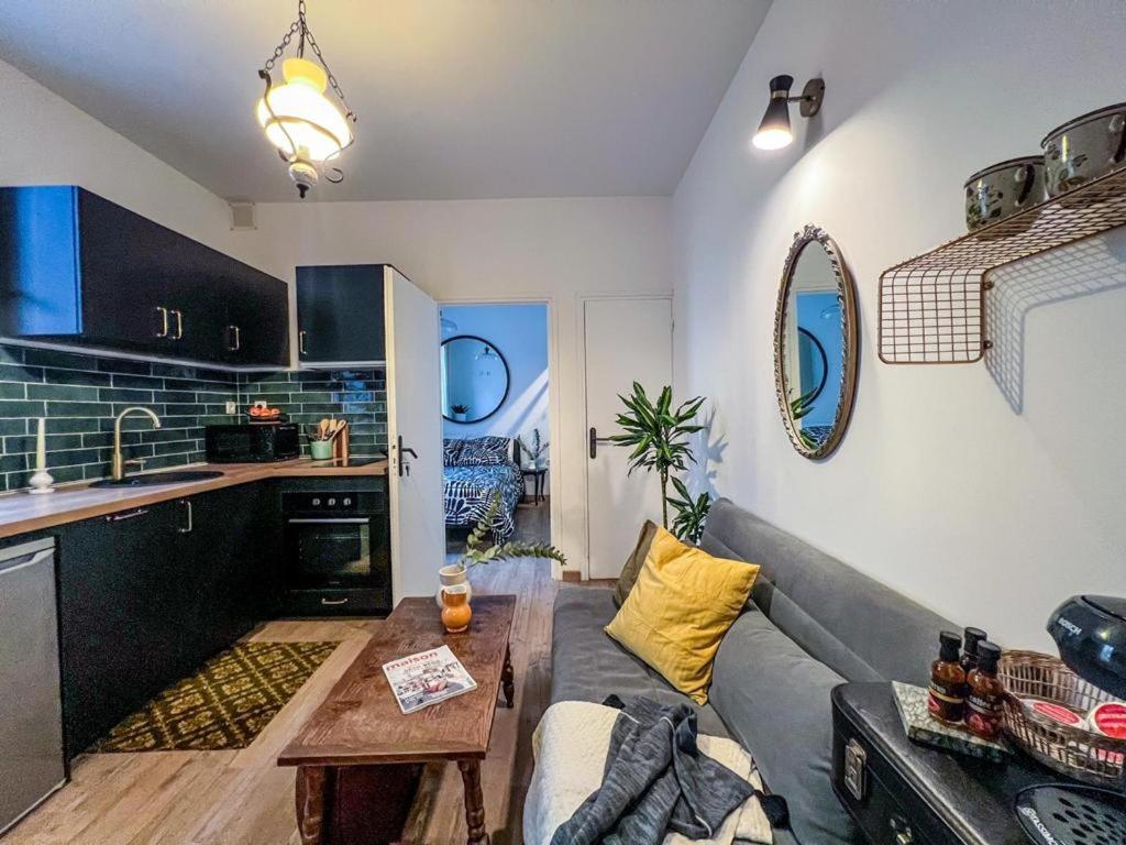 a living room with a gray couch and a kitchen at Confort & modernité au centre de Tarbes in Tarbes