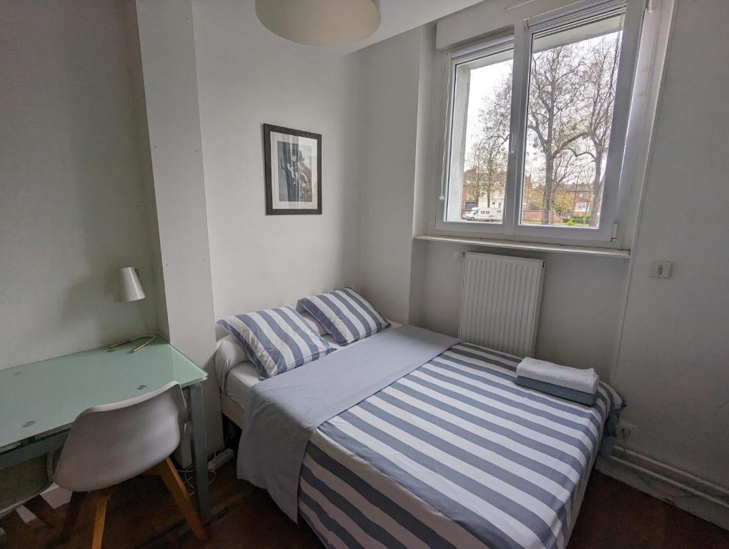 a bedroom with a bed and a desk and a window at Cosy Studio Amiens in Amiens