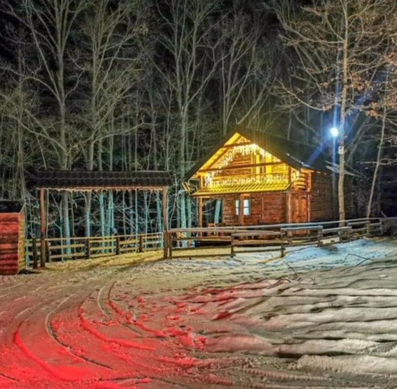 una cabaña de madera en la nieve por la noche en Vikendica Kozara en Kozarac