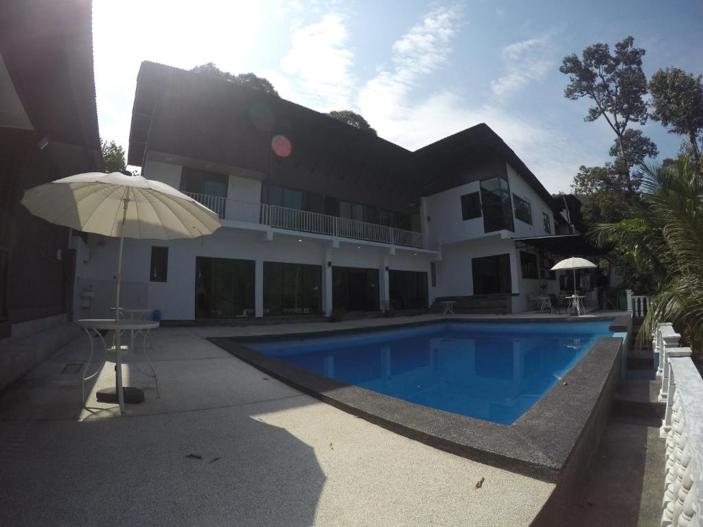 ein Haus mit Pool und Sonnenschirm in der Unterkunft Santai De Lui Resorts in Kampong Mesjid
