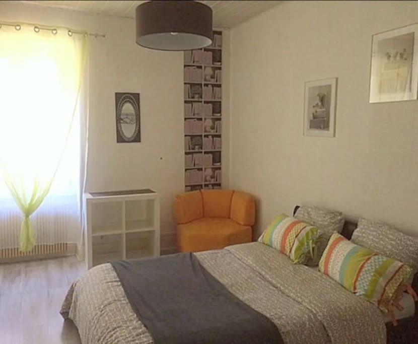 een slaapkamer met een bed en een oranje stoel bij Agréable F3 - RDC (2 chambres) in Mulhouse