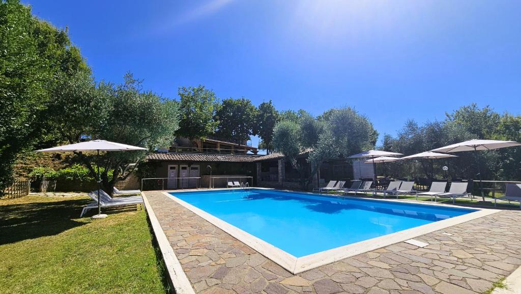 a swimming pool in a yard with chairs and umbrellas at Pian della Bandina in Città della Pieve