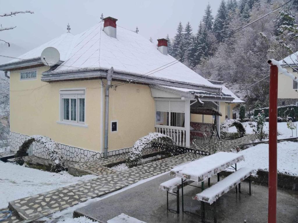 dom pokryty śniegiem z ławkami przed nim w obiekcie Casa Denisa w mieście Borsa