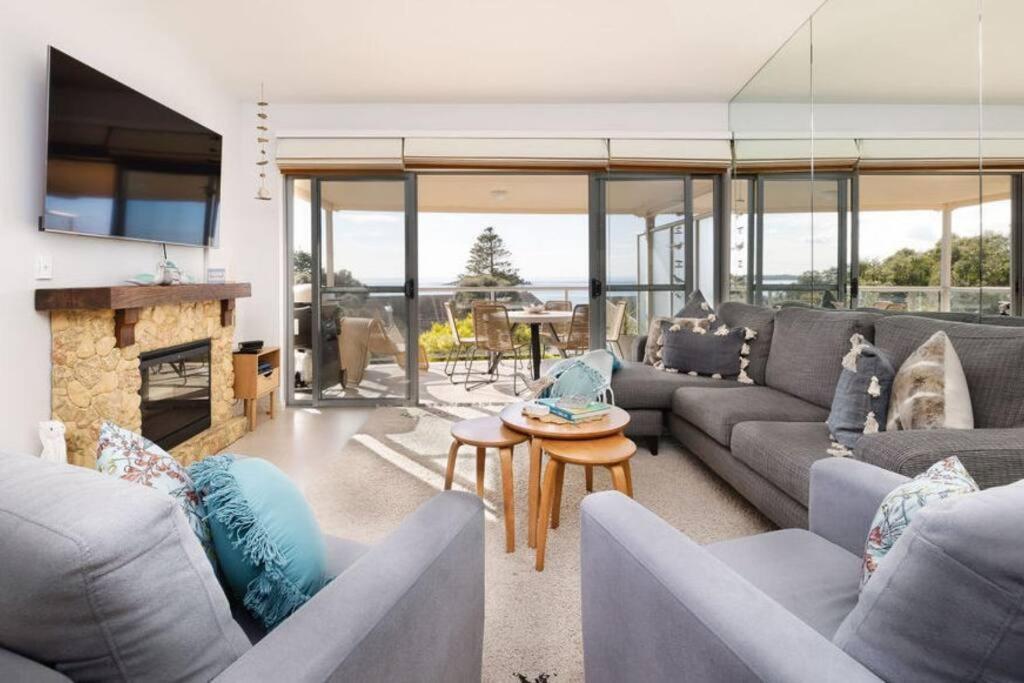a living room with couches and a fireplace at The Salty Seagull – ocean-view luxe! in Encounter Bay