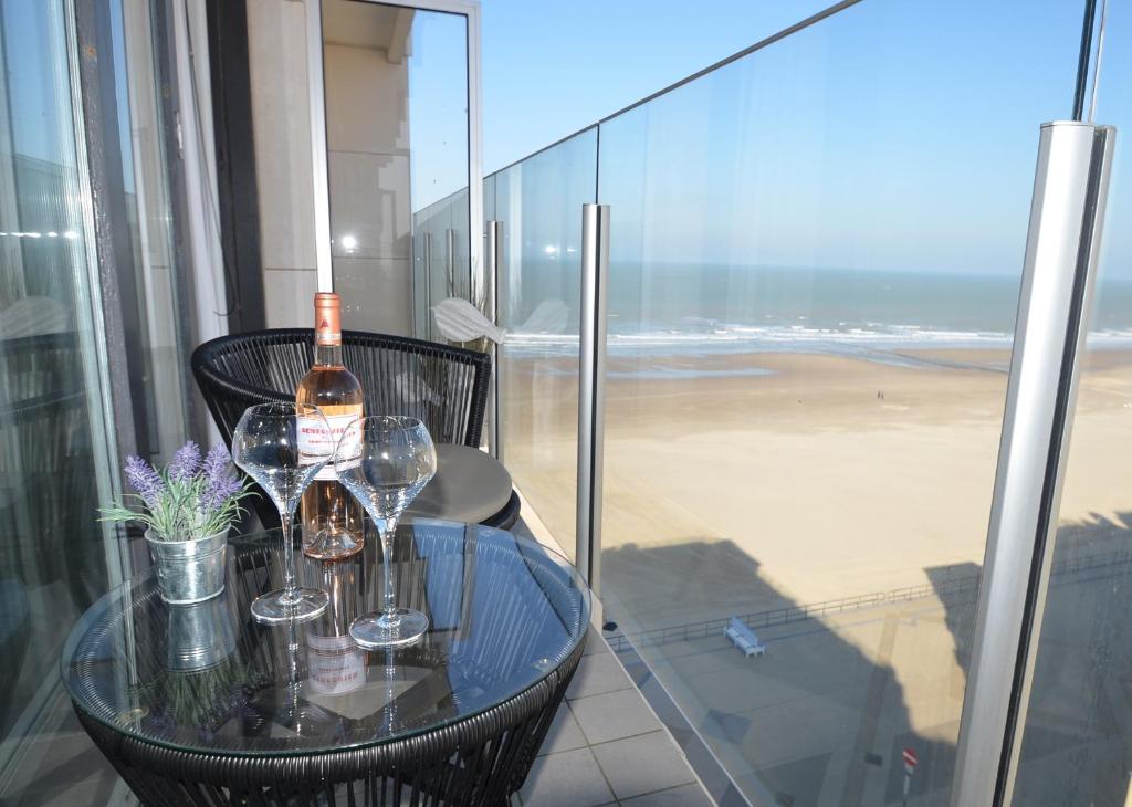 una mesa con copas y una botella de vino en el balcón en An's seaview Middelkerke, en Middelkerke