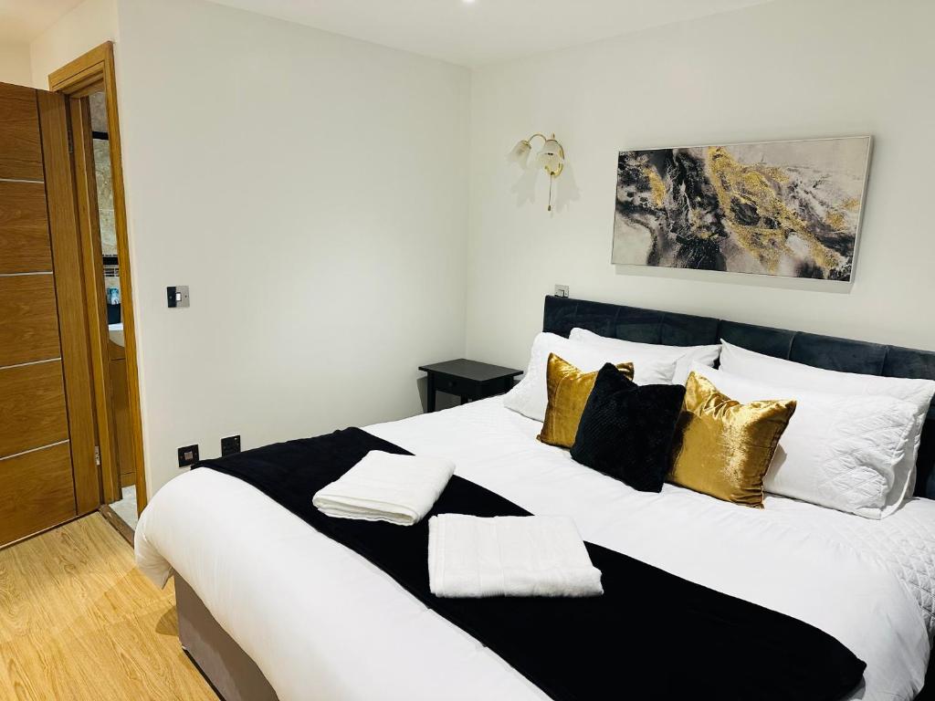 un grand lit blanc avec des oreillers noirs et dorés dans l'établissement Bright 2 Bedroom *2 Bathroom* 10 mins to East Croydon, à Croydon