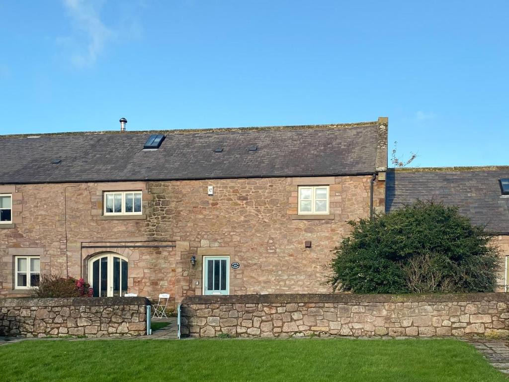 an old brick house with a stone wall at Murton Cottage in East Ord