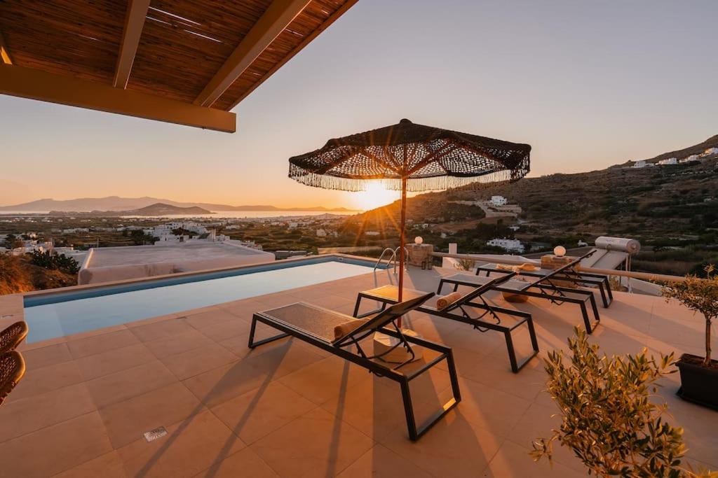 eine Terrasse mit Tischen, einem Sonnenschirm und einem Pool in der Unterkunft Pleiades Villas Naxos2 (Hottub) in Agkidia