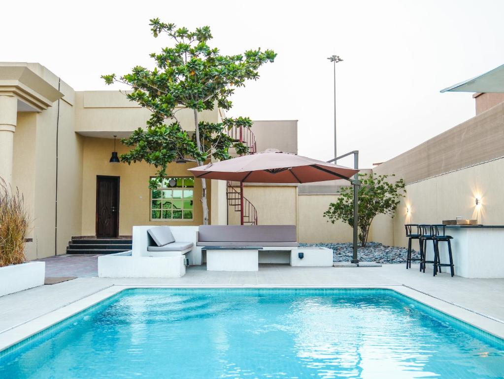 a swimming pool with a table and an umbrella at O2 pool villa in Ras al Khaimah