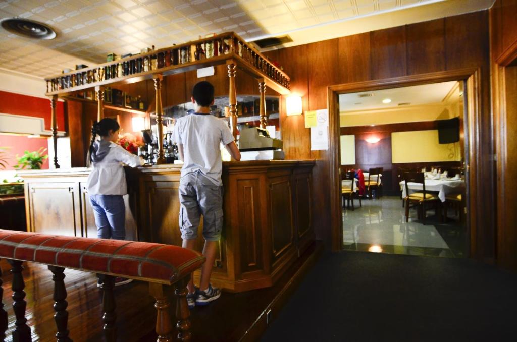 two people standing at a bar in a restaurant at Hotel Jucamar in Cangas de Morrazo