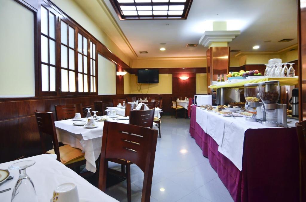 a dining room with white tables and chairs in a restaurant at Hotel Jucamar in Cangas de Morrazo