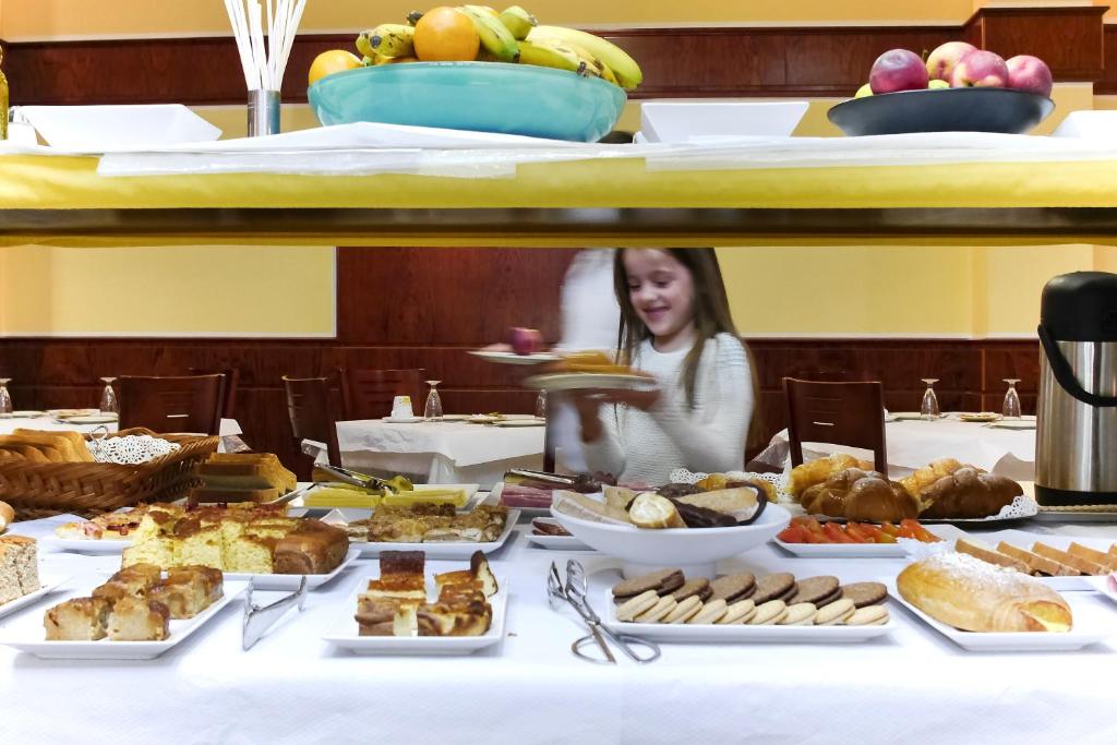 a table full of food with a little girl behind it at Hotel Jucamar in Cangas de Morrazo