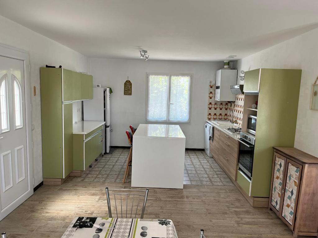 une cuisine avec des placards verts et un comptoir blanc dans l'établissement La maison POP, à Saint-Gaudens
