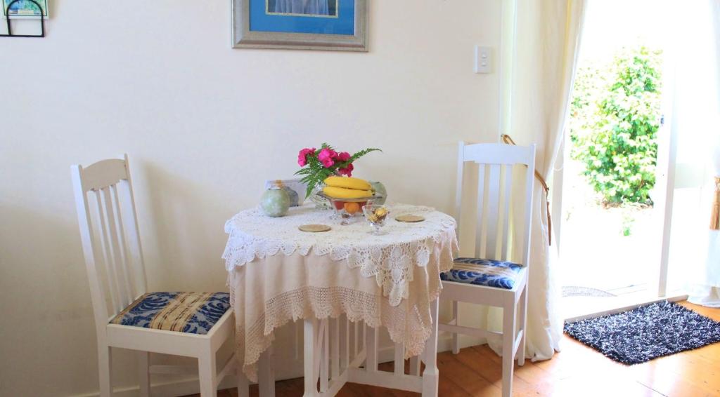 einen Tisch mit zwei Stühlen und eine Vase mit Blumen darauf in der Unterkunft Annies B and B in Warkworth