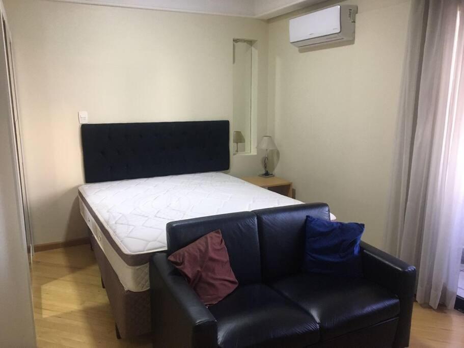 - une chambre avec un lit et un canapé en cuir dans l'établissement Hotel Bienal Suites- Rua Sena Madureira,1225, à São Paulo