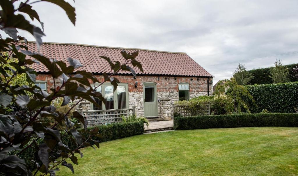 a brick house with a lawn in front of it at Stables Cottage in Selby