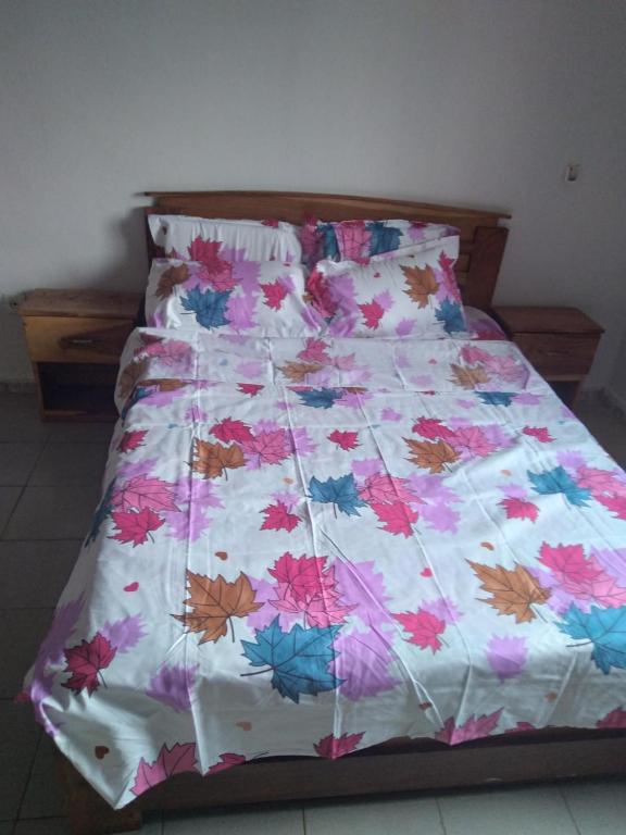 Bett mit Blumendecke in einem Schlafzimmer in der Unterkunft Le Tounkaranké résidence de Fasso Kanu - Villa- in Bamako