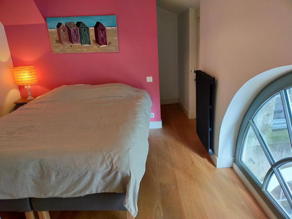 - une chambre avec un lit et un mur rose dans l&#39;établissement La Suite 14, à Cholet