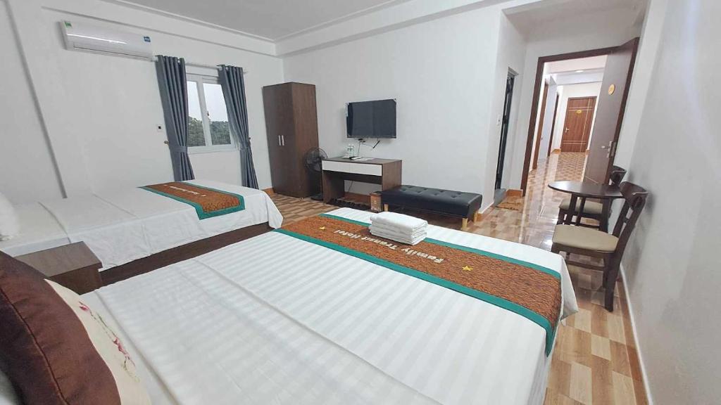 Thach Loi的住宿－家庭過境酒店，一间卧室配有两张床、一张桌子和一台电视。