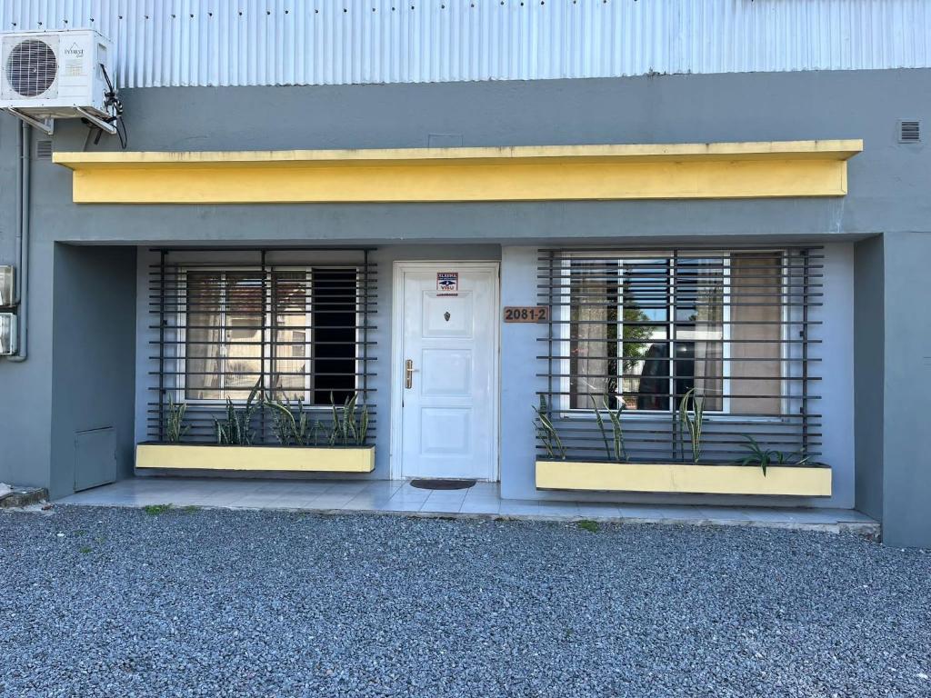 un edificio con dos ventanas y una puerta blanca en RELAX II en Paysandú