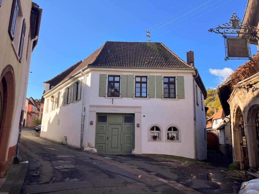 ein weißes Haus mit grünen Türen auf einer Straße in der Unterkunft Ferienwohnung Unterm Schloß in Neustadt an der Weinstraße