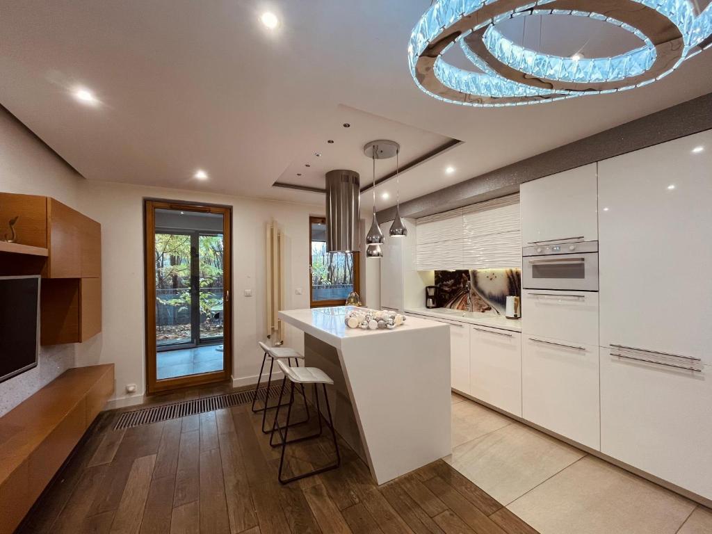 a kitchen with white cabinets and a large chandelier at Apartament Mecenasa in Krakow
