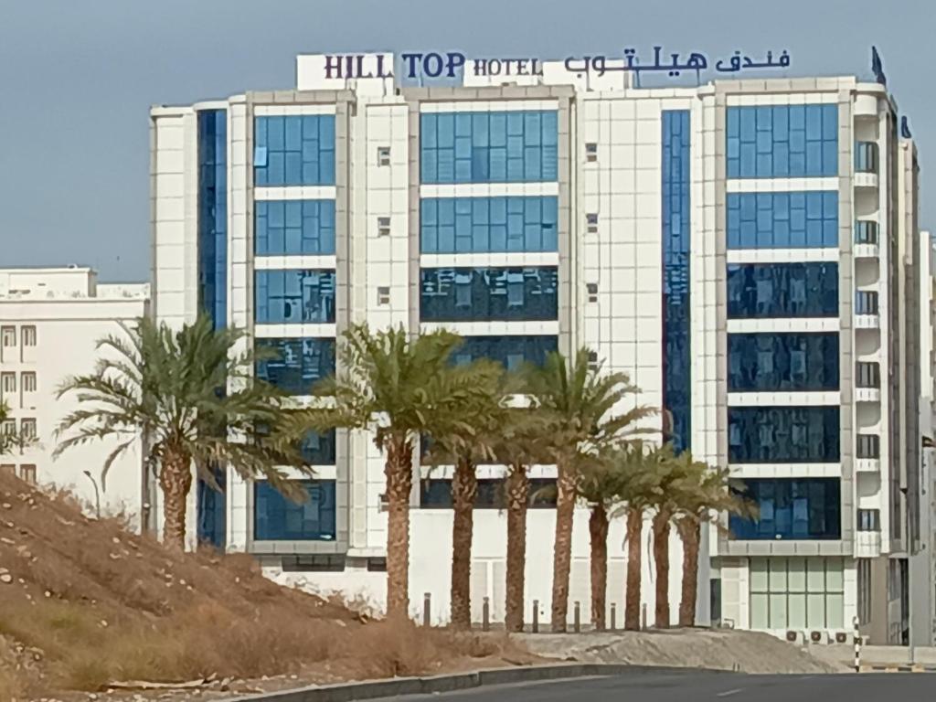 een groot gebouw met palmbomen ervoor bij Hill Top Muscat in Muscat
