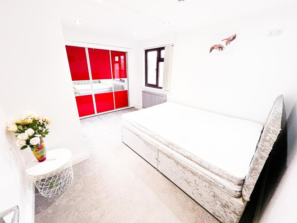 a white bedroom with a bed and red cabinets at 81 Theydon park road in Theydon Bois