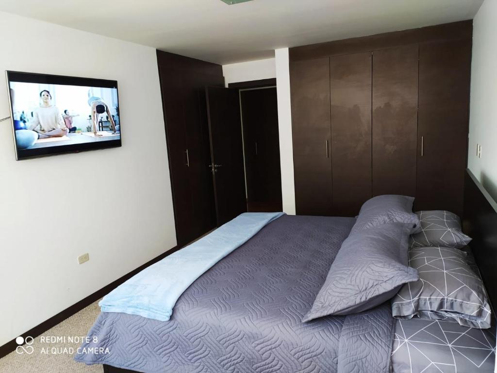 Schlafzimmer mit einem Bett und einem TV an der Wand in der Unterkunft SUITES NOA QUITO, LA CAROLINA.- in Quito