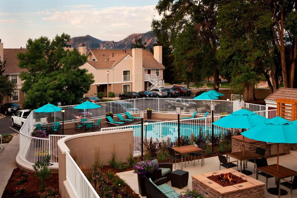 una piscina con mesas, sillas y sombrillas azules en Residence Inn by Marriott Boulder, en Boulder