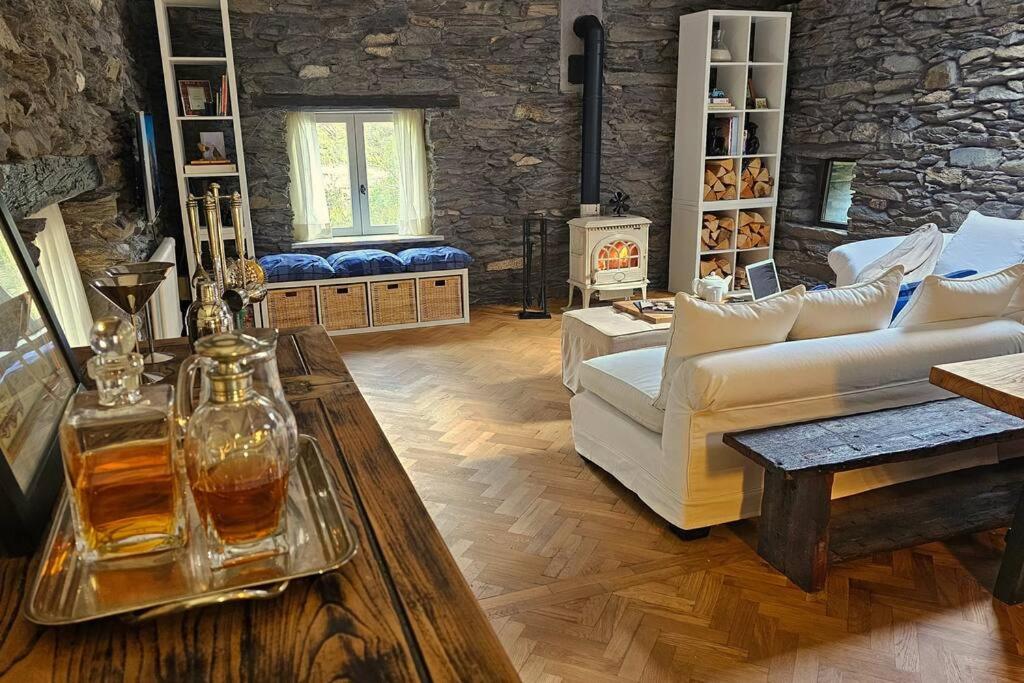 a living room with white furniture and a stone wall at Exceptional stone mountain house in Saint-Michel-de-Maurienne