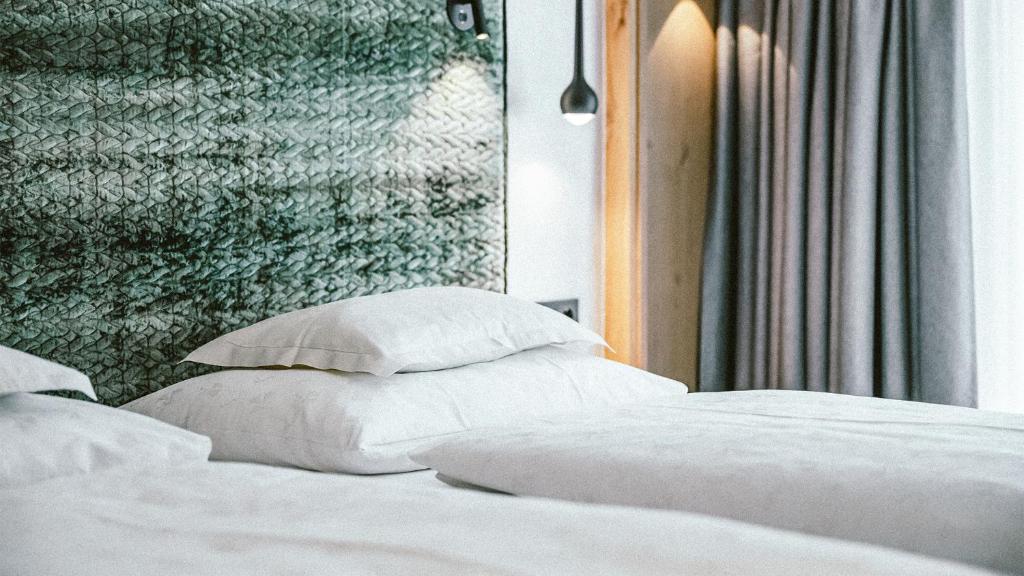 1 cama con almohadas blancas y pared verde en Gourmet & Wine Hotel Austria - 4 Sterne superior, en Obergurgl