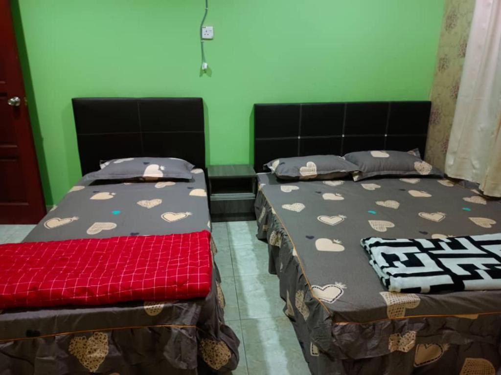 two beds in a room with green walls at Roomstay Kuala Terengganu in Kuala Terengganu