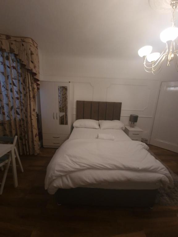 a bedroom with a large white bed with a chandelier at 51 Nonsuch Walk, Cheam in Cheam