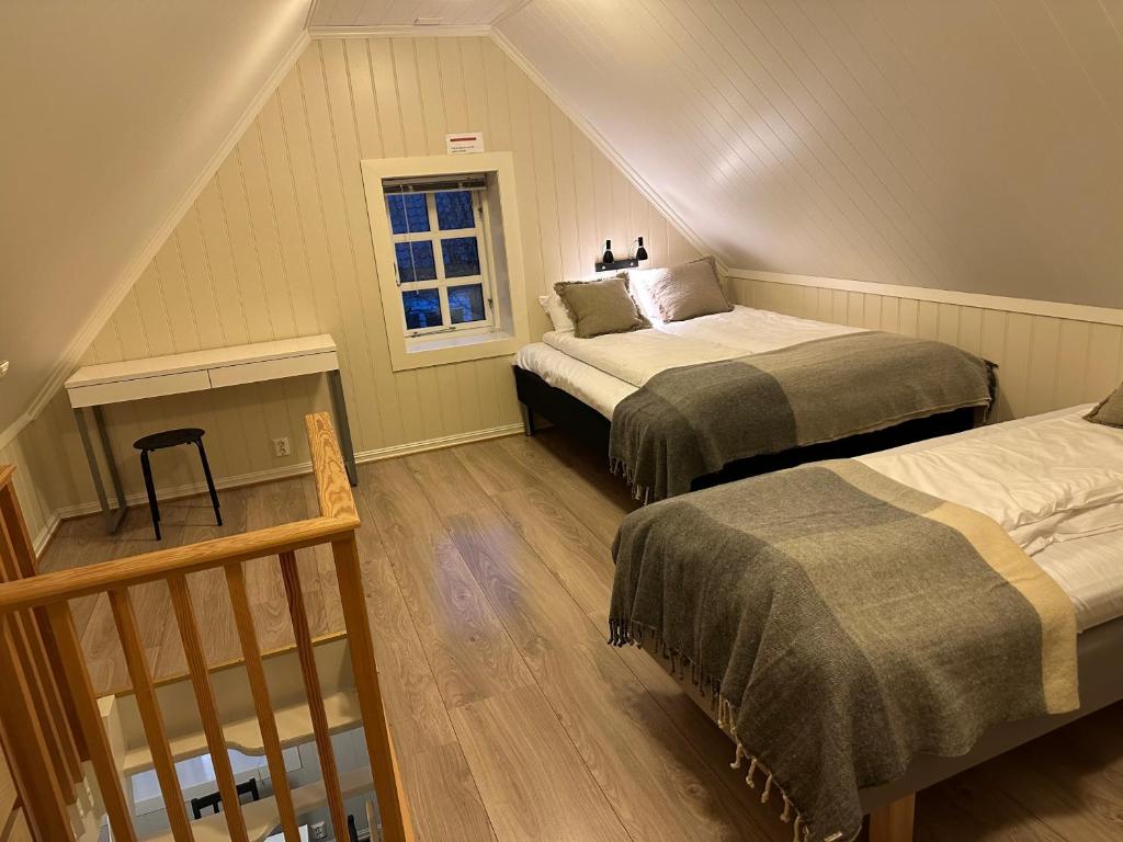 a attic bedroom with two beds and a window at Tollgaarden Gjestegaard in Larvik