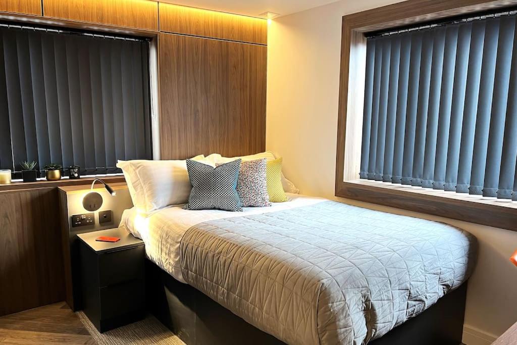a bedroom with a bed and two windows with blinds at Deluxe 1 Bed Studio -2C- near Royal Infirmary & DMU in Leicester