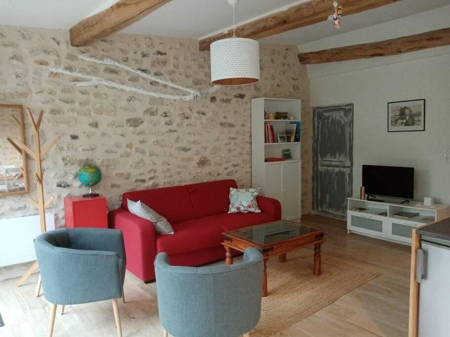 un salon avec un canapé rouge et une table dans l'établissement Gîte de charme à proximité de Fontainebleau et Moret sur Loing, à Valence-en-Brie