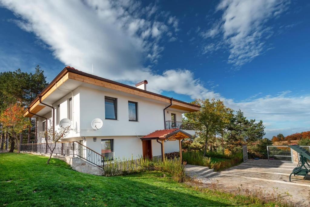a white house with a green yard at ВИЛА МАРИНОВИ in Boykovo