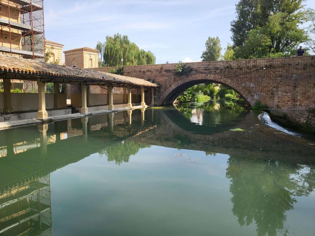 un puente sobre un río con un reflejo en el agua en Appartamento davanti al Porto Romano en Bevagna