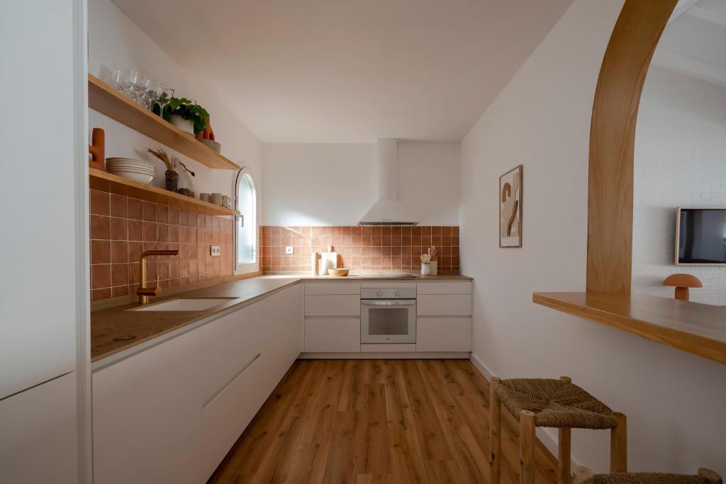 a kitchen with white cabinets and wooden floors at Villa Tropico - Design house with pool in Corralejo in Corralejo