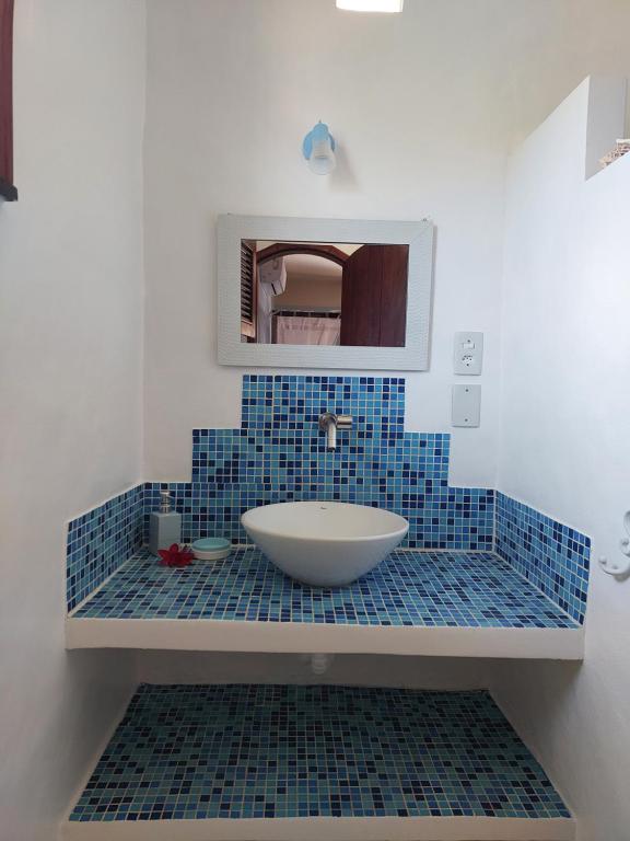 a blue tiled bathroom with a sink and a mirror at Manga Rosa Hospedagem in Canoa Quebrada
